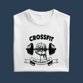 A folded white crewneck t-shirt with a black graphic print of a hand gripping a barbell under the word 'CROSSFIT' and above a banner reading 'HARD ATHLETIC GYM', displayed on a solid olive green background.